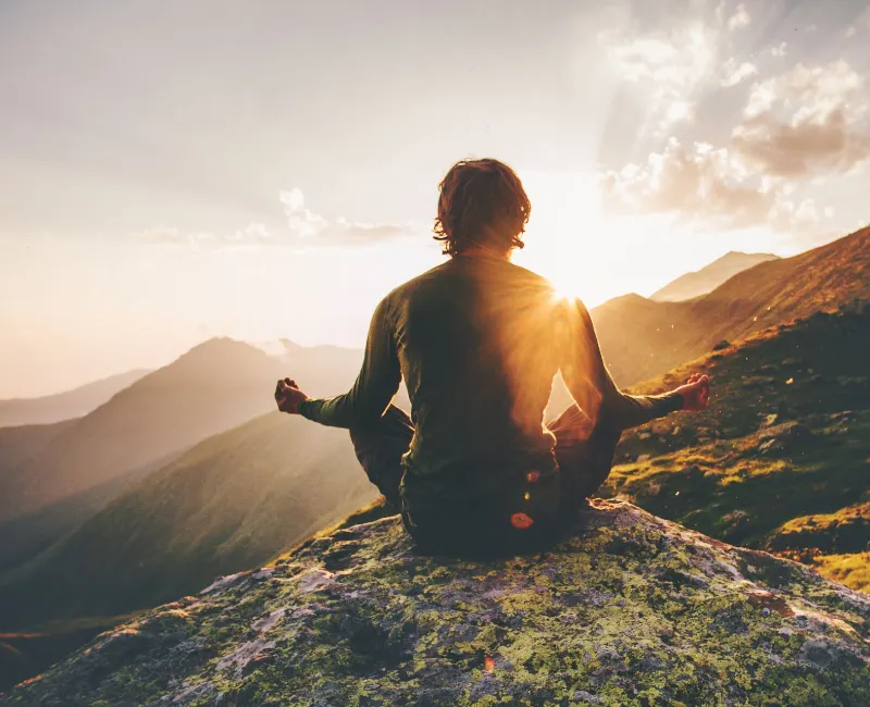 Man meditating yoga on top of the mountain with sunset and mountain view