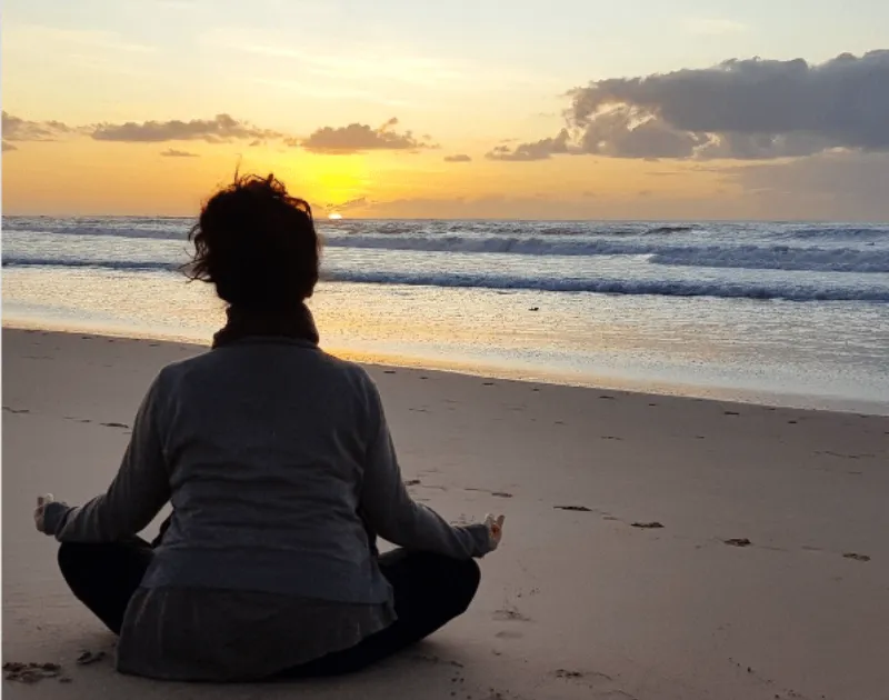 Woman sitting at the shore meditating